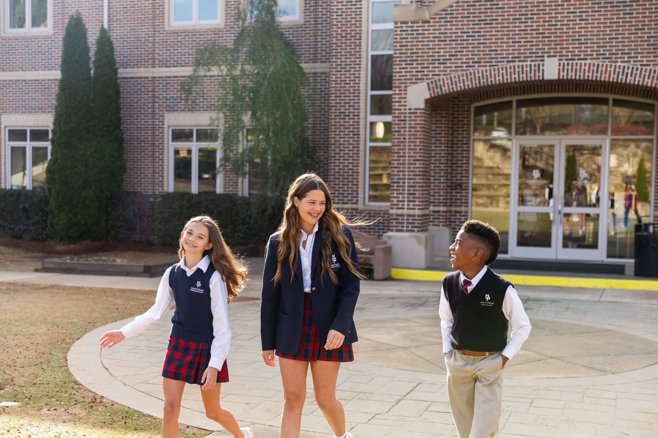 Three students walking outside, smiling